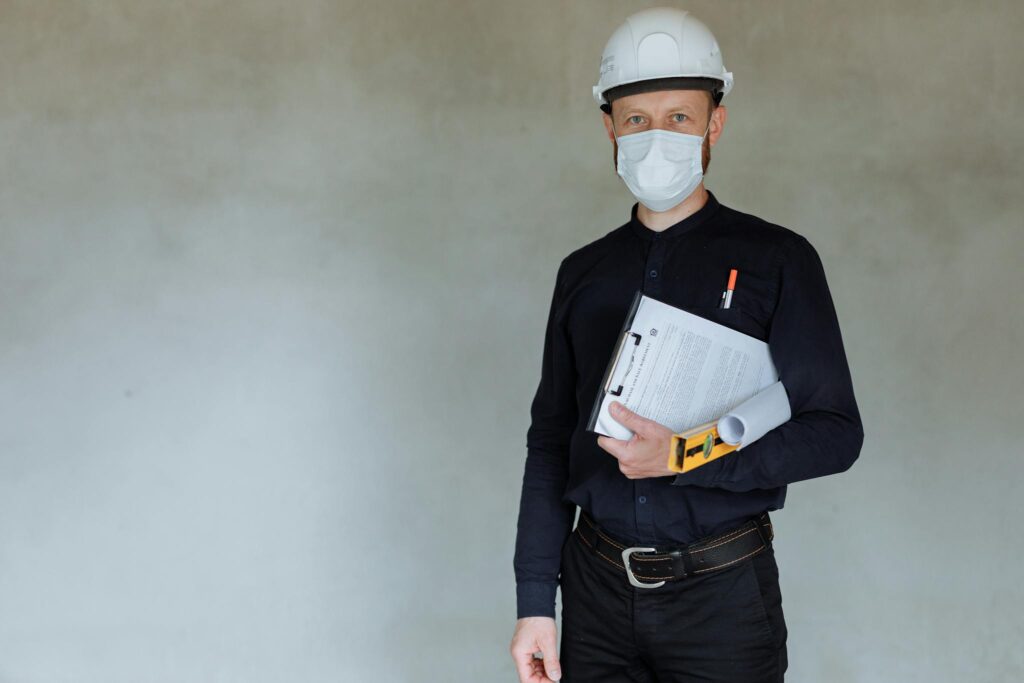 Construction worker wearing safety gear and holding documents during pandemic.